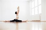 Side view of woman in exercise arms raised doing the splits