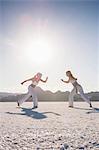 Surface level view of two women performing capoeira on Bonneville Salt Flats, Utah, USA