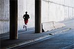 Young male runner running in city underpass