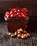 Food, rustic punnet full of cranberries and hazelnuts, wooden table