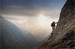 Climber on a rocky wall above a valley, Alps, Canton Bern, Switzerland