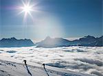 Two climbers on a snowy slope above a sea of fog in an alpine valley, Alps, Canton Wallis, Switzerland