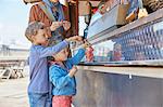 Mother and sons buying strawberries for food stall