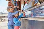 Mother and sons buying strawberries for food stall