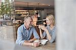 View through window of mature couple in coffee shop chatting