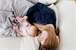 Overhead view of mid adult woman feeding baby daughter on sofa