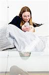 Mid adult woman feeding bottle to baby daughter on sofa