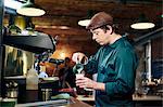 Male barista pouring milk in coffee shop