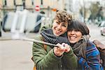 Two sisters, taking self portrait using selfie stick, outdoors