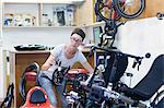 Woman in bicycle workshop checking pedal on recumbent bicycle