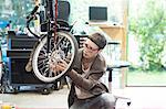 Woman in bicycle workshop repairing wheel on recumbent bicycle