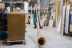 Woman in workshop testing alphorn