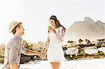 Man on one knee proposing to girlfriend on beach, Cape Town, South Africa