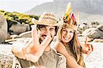 Portrait of mid adult couple making peace sign on beach, Cape Town, South Africa