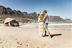 Rear view of couple wrapped in blanket  on beach, Cape Town, South Africa