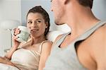 Young couple lying in bed drinking coffee