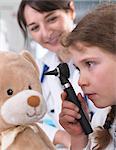 Girl using otoscope to examine teddy bear