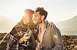 Couple in field holding wine glasses looking away