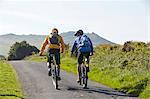 Rear view of cyclists cycling on rural road