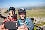 Cyclists with on rocky outcrop taking selfie