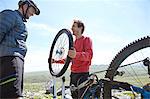 Cyclists repairing bicycle on mountainside