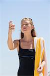 Woman spraying sunscreen on her face