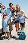 Happy young family standing by car for vacation