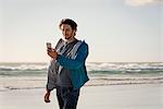 Happy young man using a phone on beach