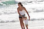 Happy mother with her little son walking on beach