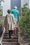 Senior couple carrying suitcase on staircase