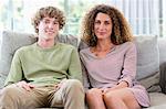 Portrait of happy mother and son sitting on couch in living room