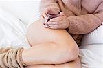 Close-up of a woman with cup of herbal tea in bed