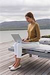 Beautiful woman using a laptop at lakeshore