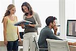 Businesswoman discussing file with her colleague with a man working on pc