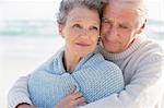 Active senior man embracing his wife from behind on the beach