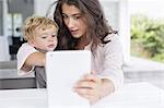 Mother and son taking selfie with digital tablet at home