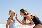 Beautiful woman applying sunscreen on her daughter face