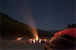 Sitting around a campfire next to the Karnali River during a rafting expedition in Nepal, Asia