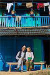 A old Nepali couple wearing traditional dress sit outside their house in Diktel, Khotang District, Nepal, Asia