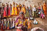 A woman sells puppets along the fort walls in Jaisalmer in the desert state of Rajasthan, India, Asia