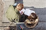 High angle view of teenage boy and girl reading book while sitting on steps