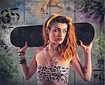 Tattooed girl with skate and murals background