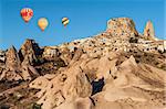 Hot air balloons flying over Cappadocia near Uchisar castle at sunrise, Turkey