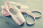 new pink ballet pointe shoes on  wooden background in vintage style