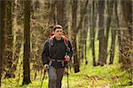 Active healthy man with red backpack hiking in beautiful forest.