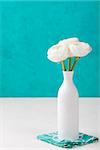 White ranunculus flowers in a ceramic vase Blue background Copy space