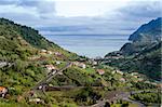 Typical landscape of Madeira island, serpentine mountain road, houses on the hills and ocean view. Aerial view to Porto da Cruz, Madeira, Portugal.