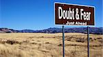 Doubt and Fear road sign with blue sky and wilderness