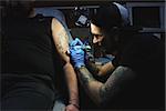 Beautiful tattooist with tunnels makes a tattoo on his leg