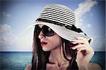 Elegant woman with hat and sea on background